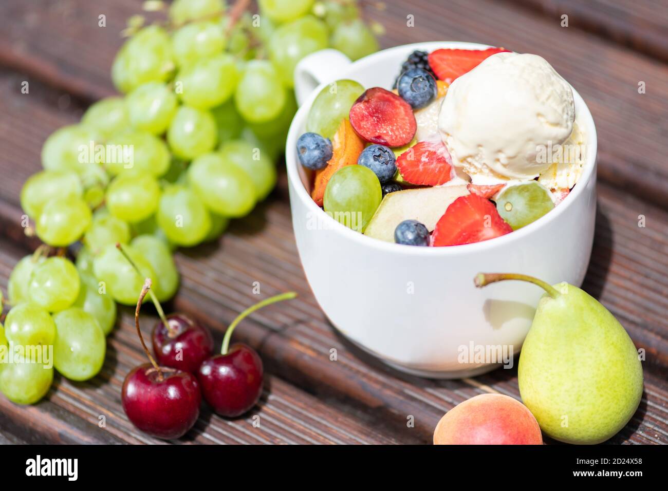 Schüssel mit gesunden frischen Obstsalat mit Eis auf dem Holzhintergrund. Stockfoto