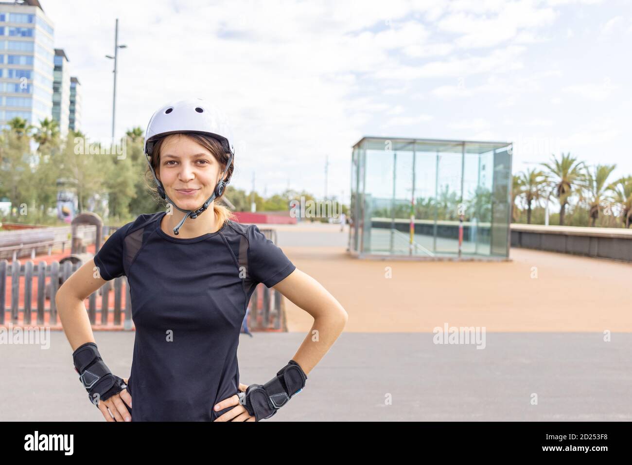 Junge glücklich Roller Skater kaukasische Frau in den weißen Helm und schwarze sportliche Kleidung an einem sonnigen Tag im Skatepark, urbane Umgebung Stockfoto