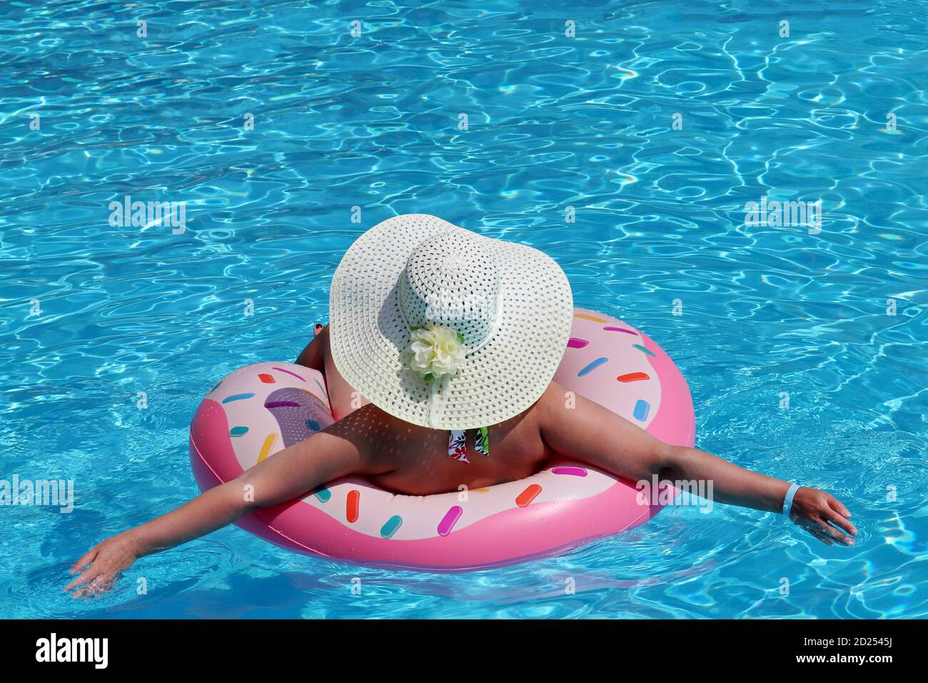 Frau in Hut und Bikini Schwimmen auf aufblasbaren Donut Ring im Pool. Strandurlaub, Entspannung und Freizeitkonzept Stockfoto