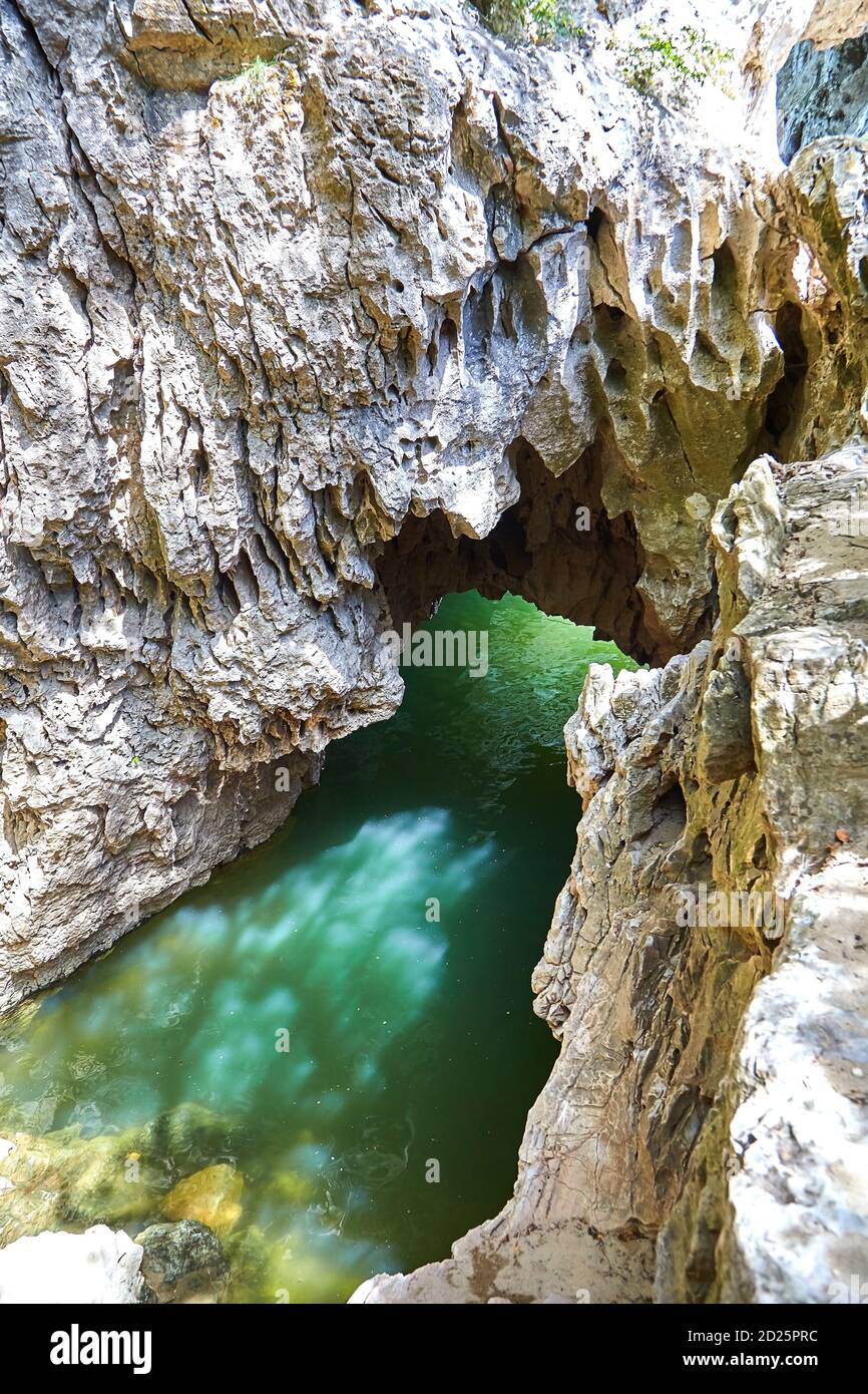 Höhle in Felsen gefüllt mit Flusswasser. Blendung auf der Steinoberfläche des Großsegels. Reflexion von Flüssigkeit an der Wand der Grotte Stockfoto