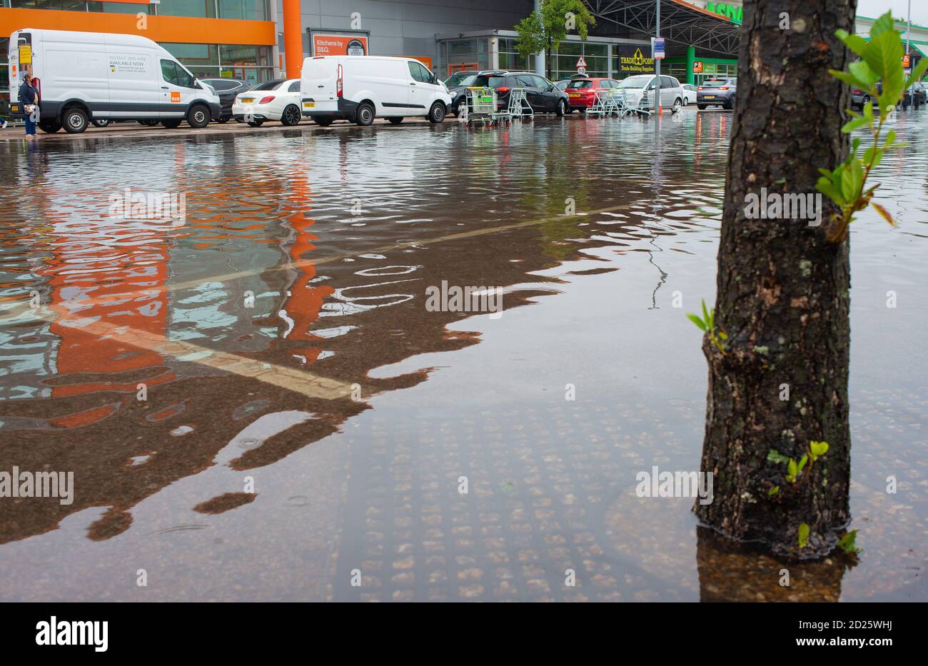 Überschwemmter Einzelhandelsparkplatz nach schweren Regenfällen eingetaucht. Die Flut hat das Fahren gefährlich gemacht, da einige Autobesitzer nicht auf ihre Fahrzeuge zugreifen können. Stockfoto