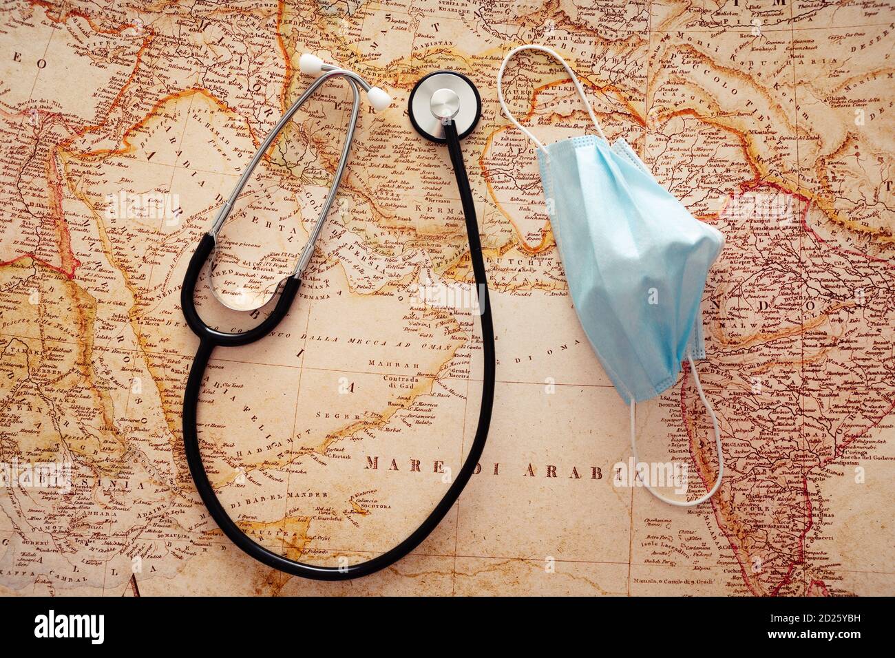 Draufsicht des medizinischen Stethoskops und der schützenden Gesichtsmaske auf dem Hintergrund der Weltkarte. Stockfoto