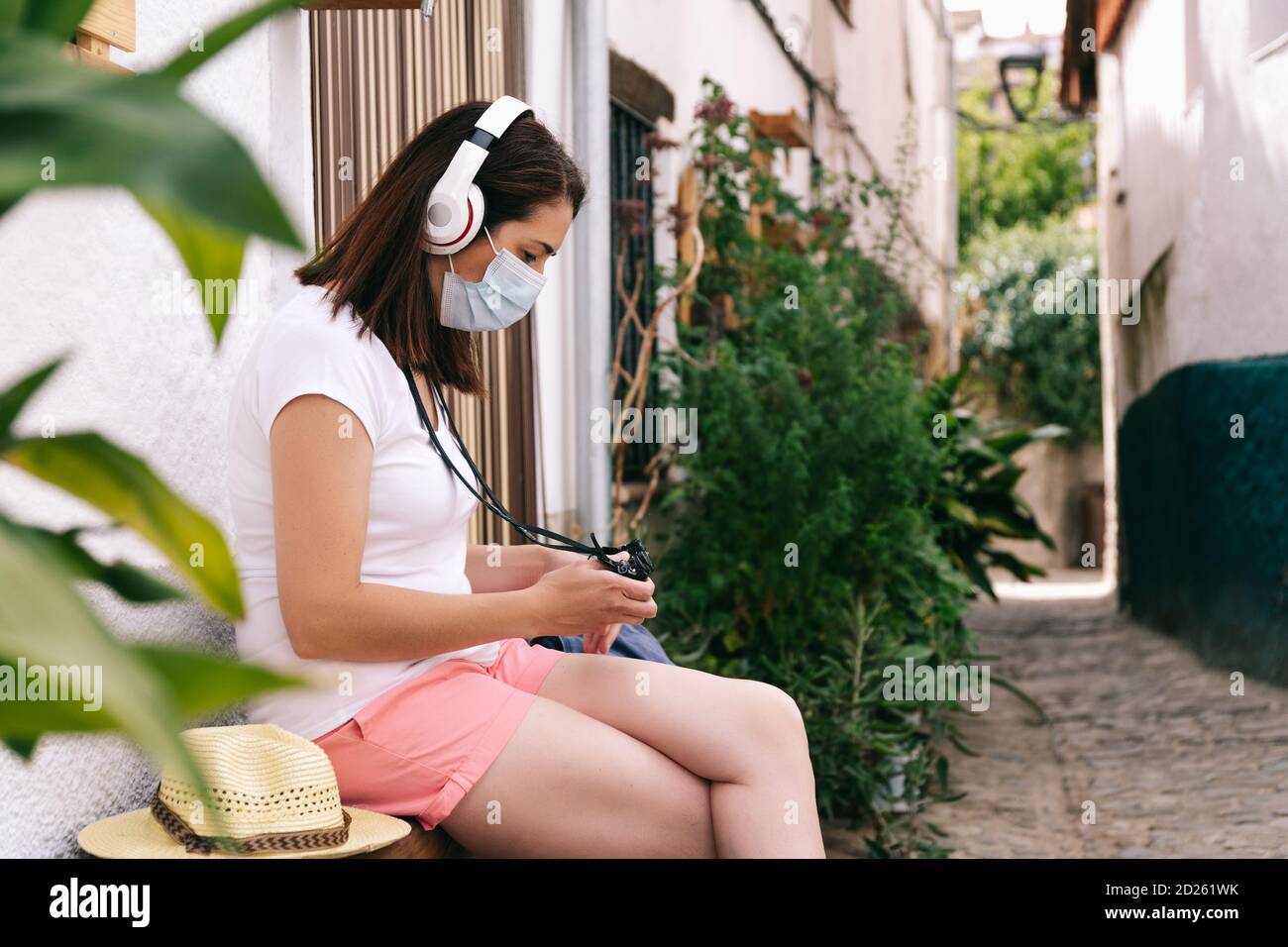 Freiberufliche Frau mit Maske Sightseeing ruht Musik hören, während Anzeigen von Fotos auf der Kamera Stockfoto