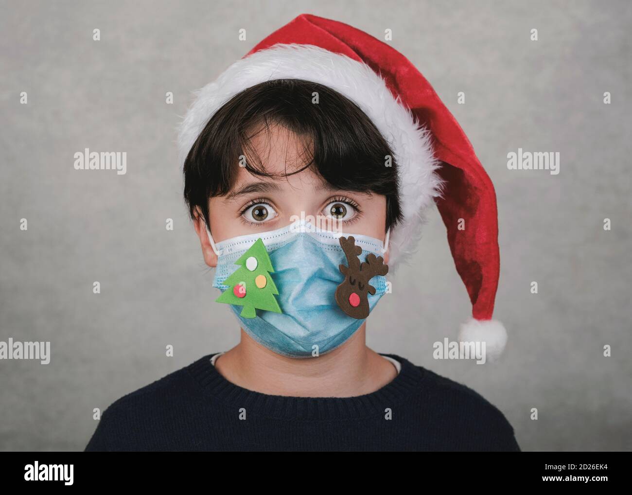 Frohe Weihnachten, Nahaufnahme von Kind mit lustigen weihnachten medizinische Maske über Grauer Hintergrund Stockfoto