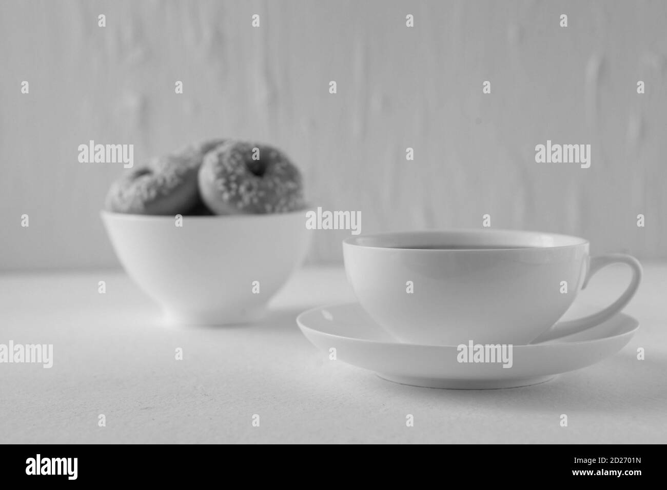 Schwarz-Weiß-Bild -Tasse heißen Kakao und Donuts auf weißem Hintergrund. Leckere süße Donuts und heiße Kakao Tasse. Süßes Frühstück Stockfoto