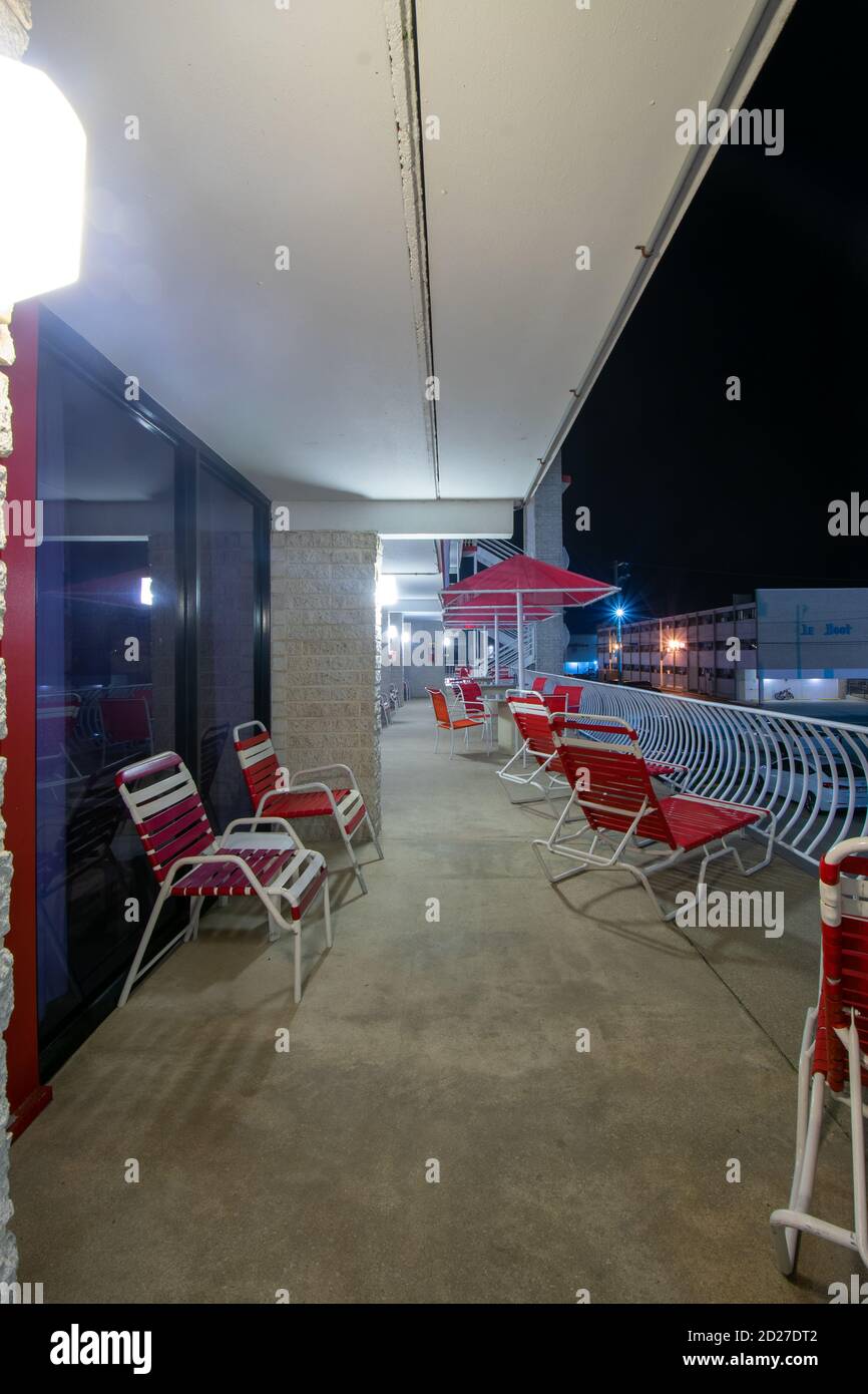 Ein leerer Hotelbalkon in der Nacht mit roten Tischen bedeckt Und Stühle Stockfoto