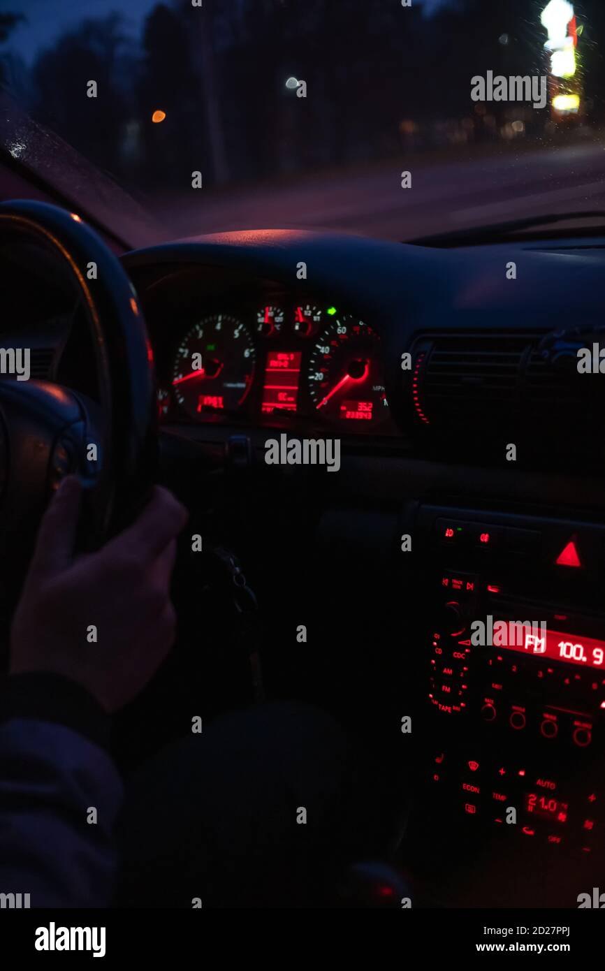 Die Hände des Fahrers am Lenkrad des Autos, fahren nachts mit dem Auto.  Fokus auf die rot beleuchtete Fahrzeugkonsole. Vertikales Foto  Stockfotografie - Alamy