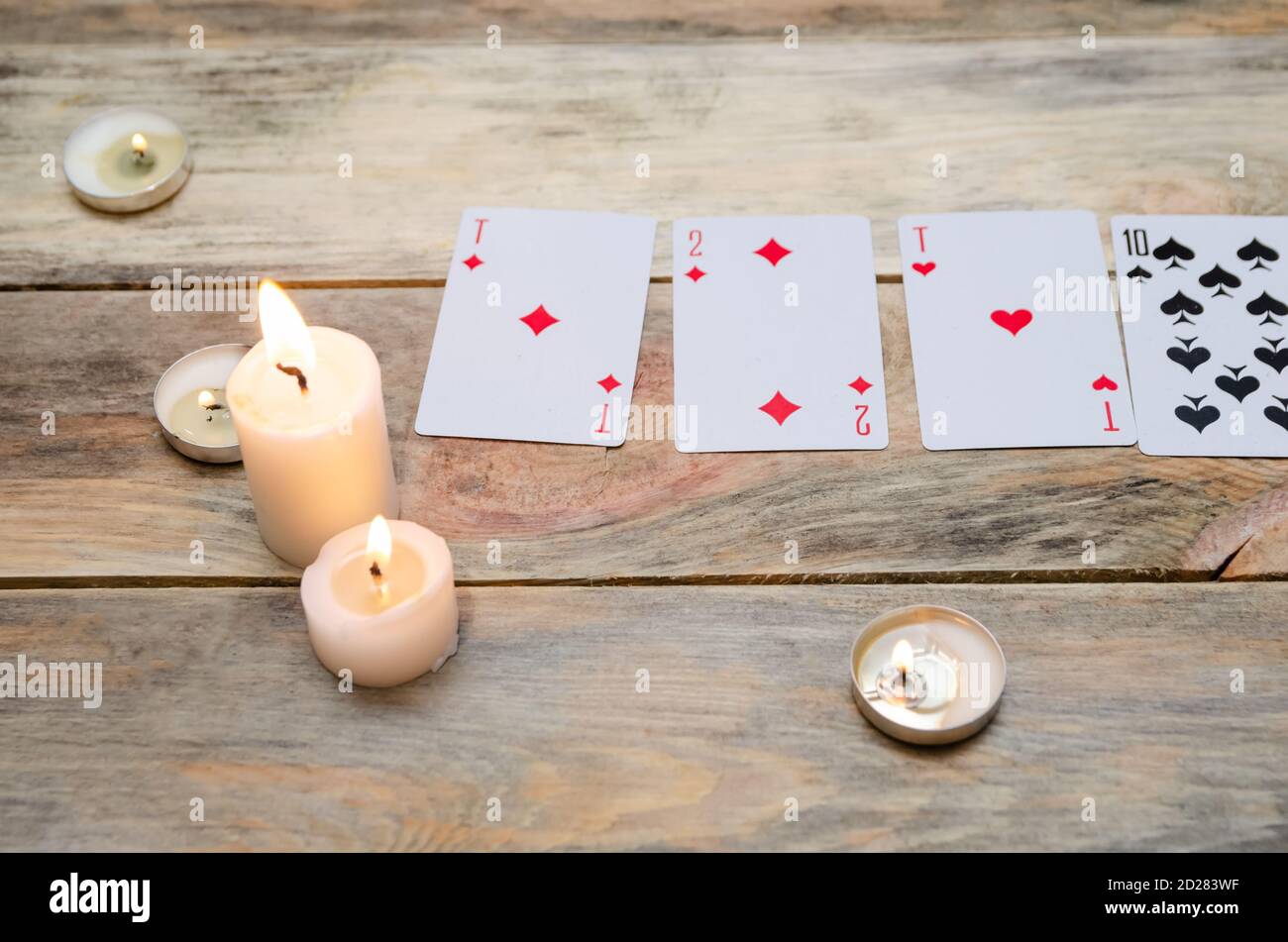 Karten für Weissagung oder Spiele, brennende Kerzen auf einem Holztisch. Konzept der Magie, Weissagung Stockfoto