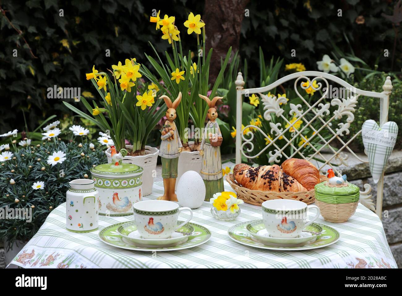 ostertisch Dekoration mit Tee Porzellan und Croissants im Frühjahr Garten Stockfoto