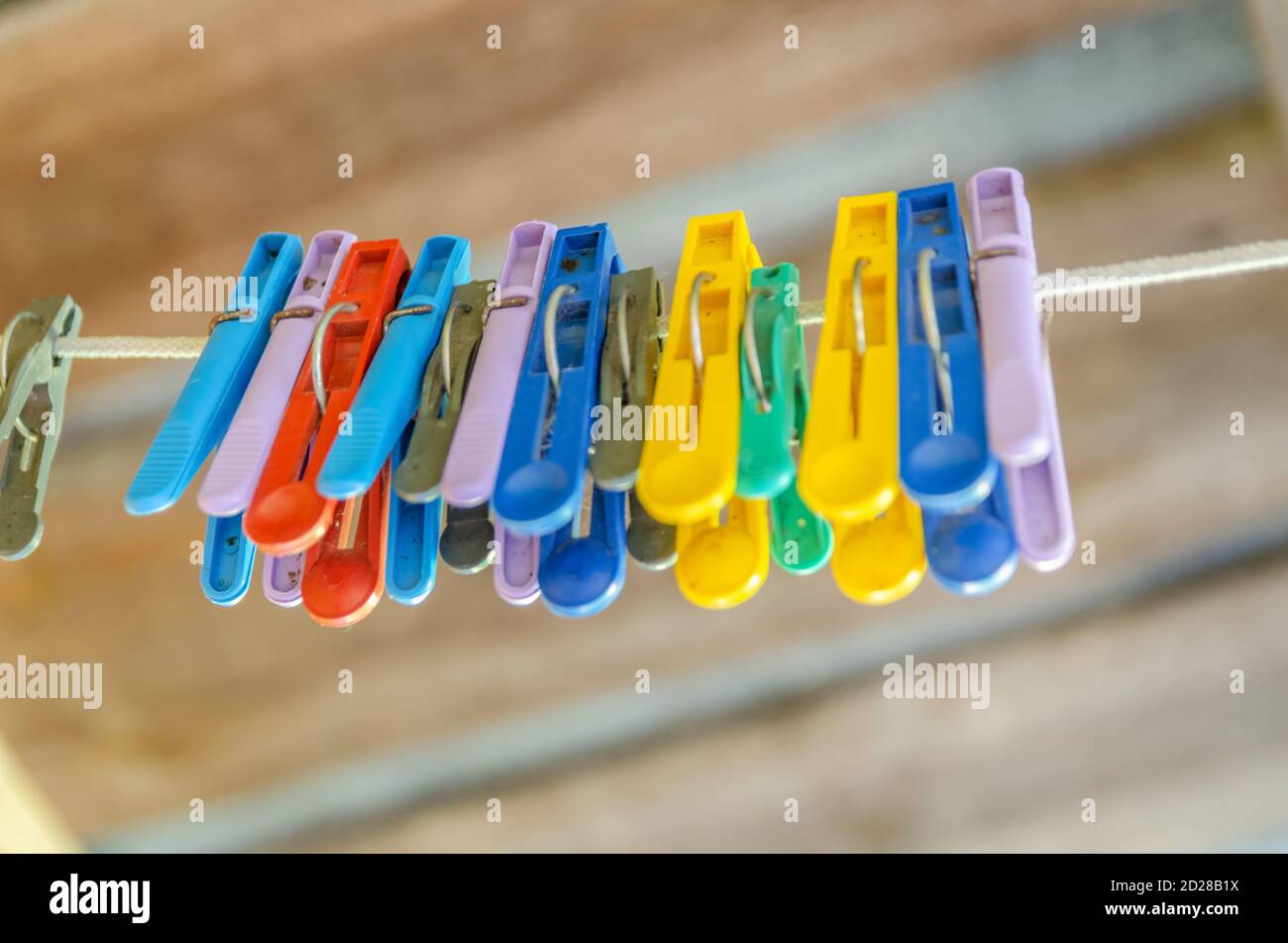 Alte farbige Kunststoff-Wäscheklammern hängen in einer Reihe an der Wäscheleine, Nahaufnahme mit geringer Schärfentiefe und Kopierraum Stockfoto