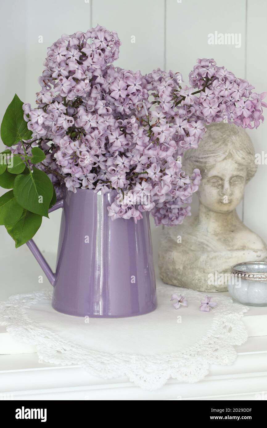 Frühlingsdekoration mit Blumenstrauß aus Flieder und Frauenbüste Stockfoto
