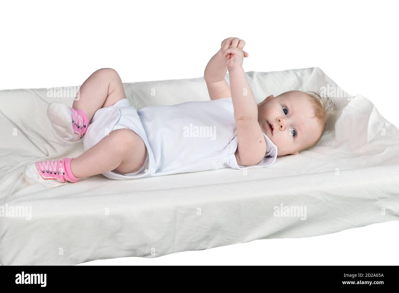 Ein vier Monate altes Baby in weißer Kleidung liegt auf dem Rücken auf einem Wickeltisch. Die Arme und Beine sind hochgehoben. Das Baby ist gut gelaunt. Isoliert Stockfoto