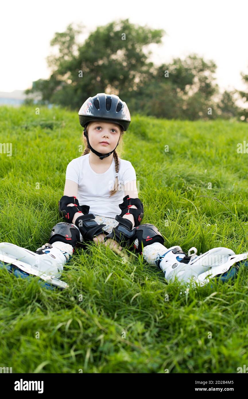 Kleine hübsche Mädchen auf Rollschuhe im Helm im Freien auf Schöner Sommertag Stockfoto