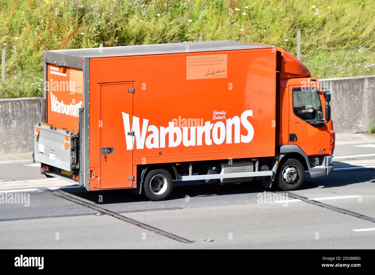 Warburtons Familienbetrieb Bäckerei Business Details beworben auf Seite von Brot Lieferung Supply Chain LKW & Heckhubwagen fahren Auf der M25 Autobahn UK Stockfoto