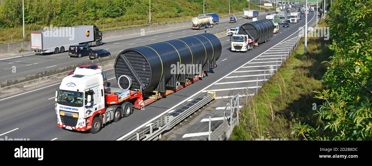 Blick nach unten auf große Übergröße lange Zylinderform Last auf Transport LKW und LKW mit Tieflader Anhänger belegt zwei Lanes M25 Autobahn England Großbritannien Stockfoto