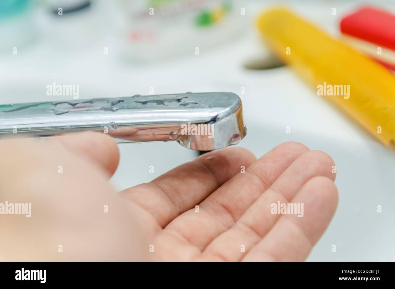 Nahaufnahme des Mannes legte seine Hand unter den Wasserhahn, das Wasser fließt nicht. Stockfoto