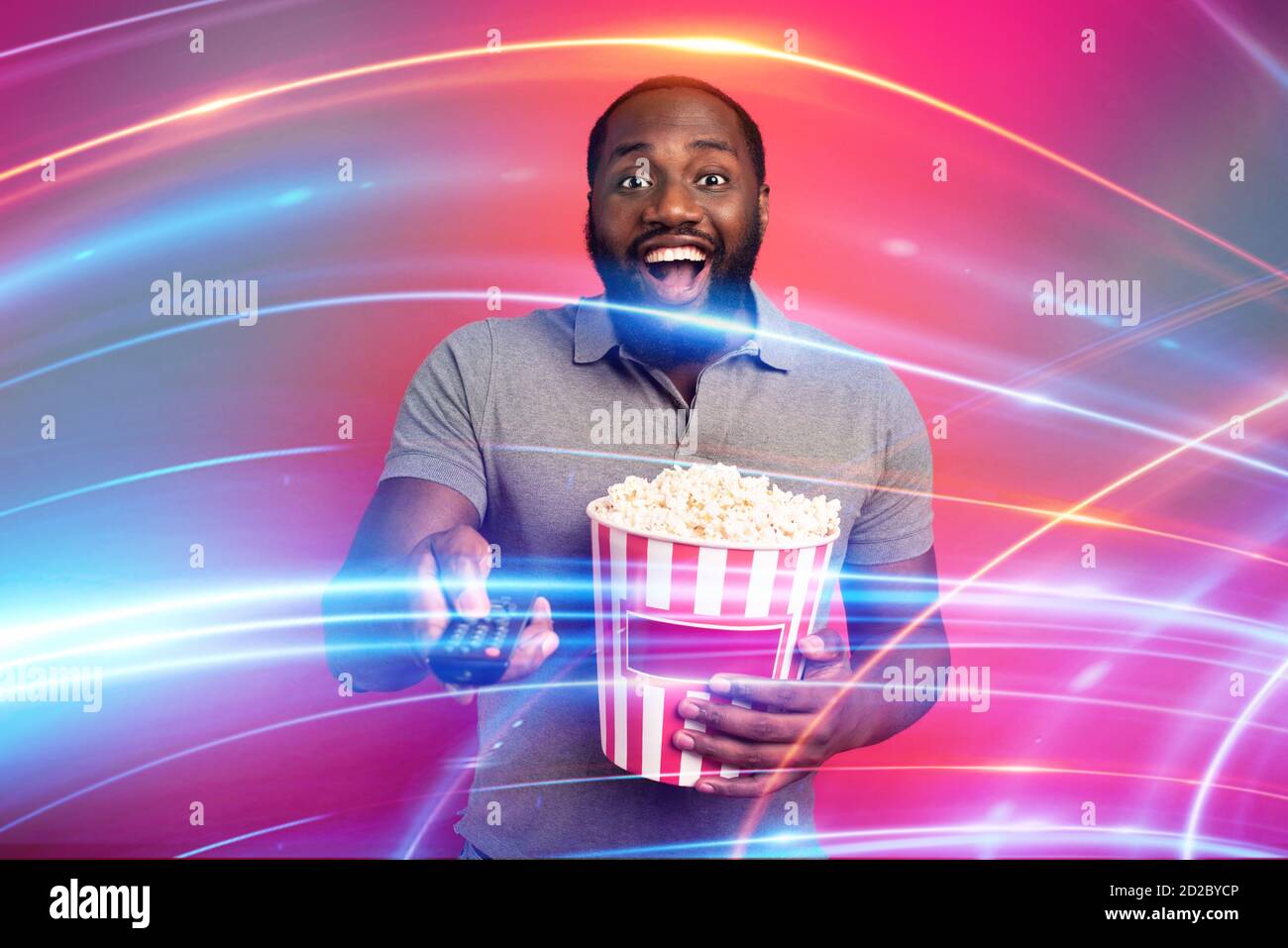 Mann hat Spaß beim Ansehen eines Films. Konzept der Unterhaltung und Streaming-tv. Roter Hintergrund Stockfoto