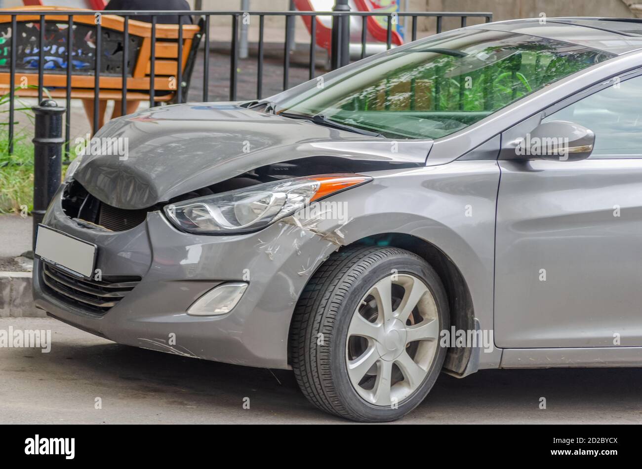 Zerknitterte Motorhaube eines grauen Autos nach einem Unfall wird ein Teil über dem Rad mit Klebeband verklebt Stockfoto