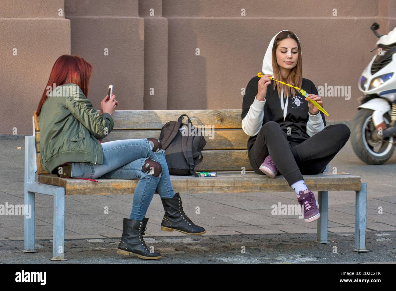 Zrenjanin, Serbien, 05. Oktober 2019. Zwei Mädchen, Studenten, ruhen auf einer Bank im Stadtzentrum. Sie genießen einen schönen angenehmen Tag und frische Luft. Stockfoto