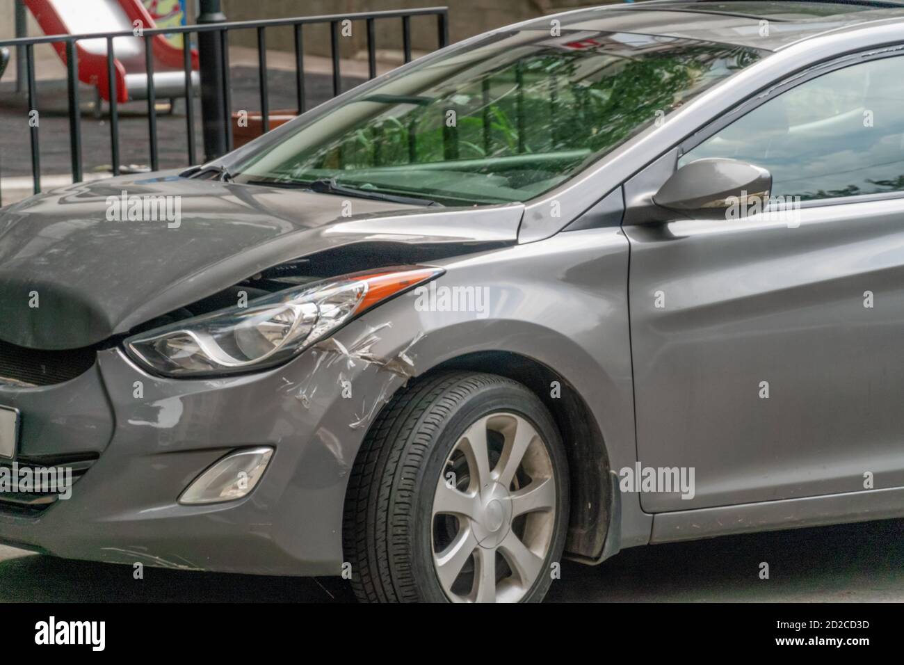 Zerknitterte Motorhaube eines grauen Autos nach einem Unfall wird ein Teil über dem Rad mit Klebeband verklebt Stockfoto