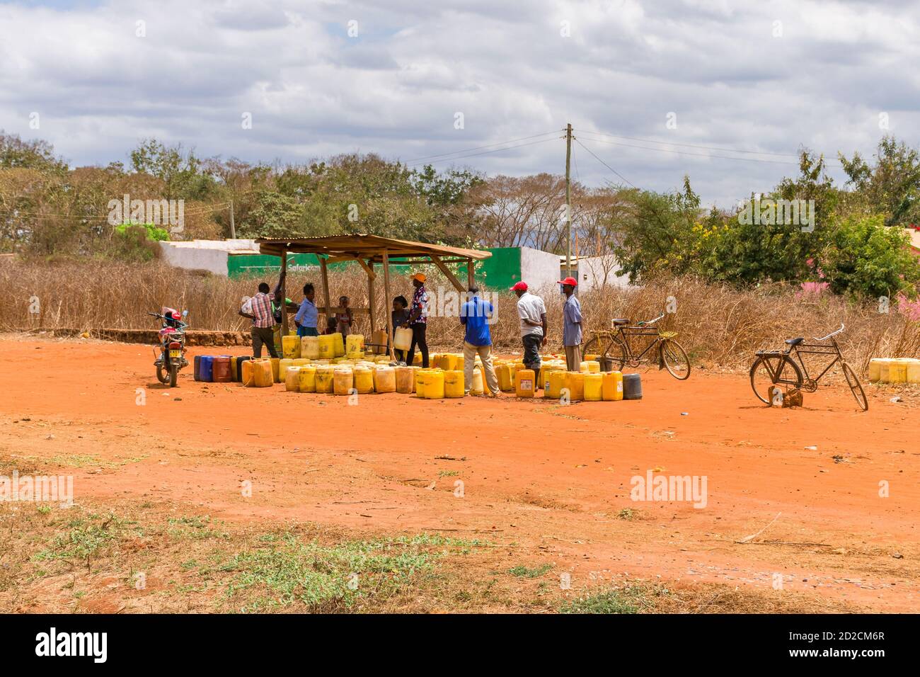 Eine Gruppe lokaler Kenianer, umgeben von gelben Wasserbehältern im ländlichen Kenia in Ostafrika Stockfoto