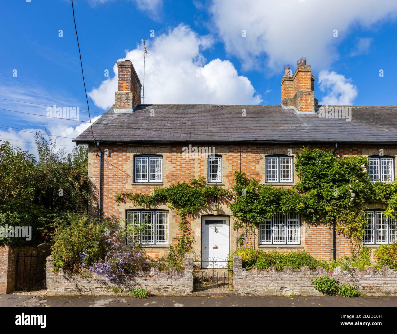 Ferienhaus am Straßenrand mit attraktivem, lokalem gemustertem Mauerwerk in Great Bedwyn, einem Dorf im Osten von Wiltshire, Südengland, an einem sonnigen Tag Stockfoto