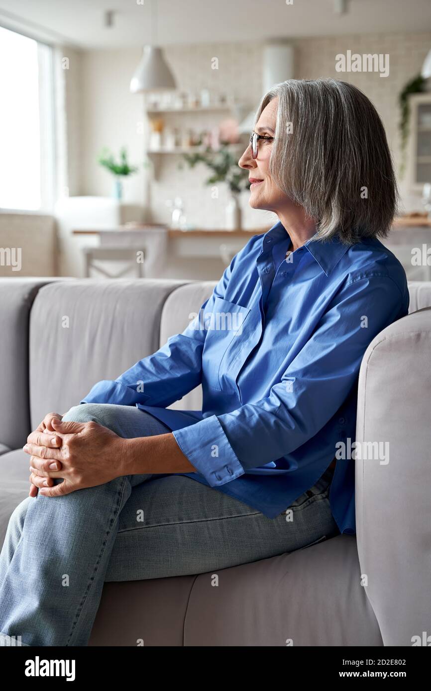 Stilvoll entspannt ältere Frau entspannt sitzen auf Couch zu Hause. Stockfoto