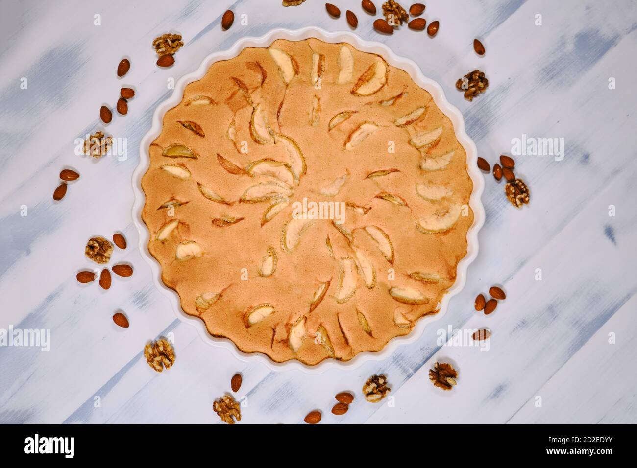 Apfelkuchen mit Nüssen, Draufsicht. Hausgemachte Kuchen reife Äpfel auf weißem Holz Hintergrund. Obstkuchen mit Mandeln und Walnüssen. Stockfoto