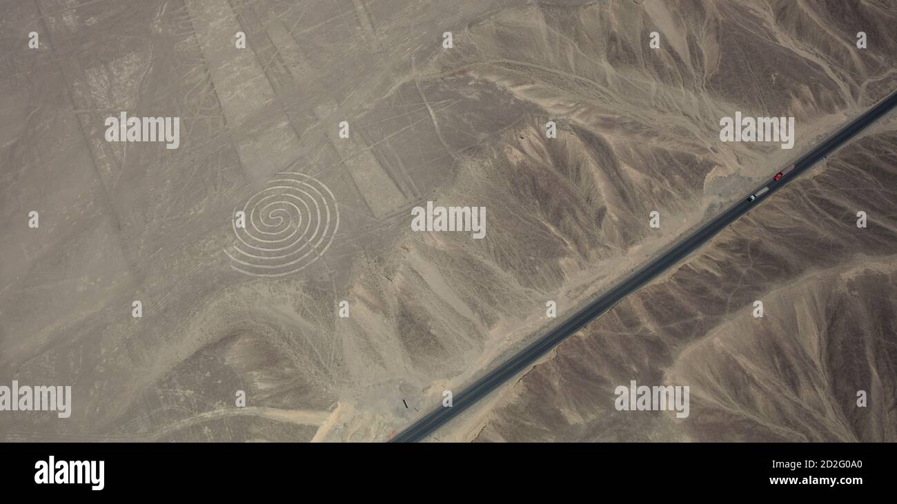 Zwei Lastwagen auf dem Pamamerican oder Inter-American Highway erweitern diese Luftaufnahme des Spiral-Geoglyps in den Nazca Lines, Peru Stockfoto