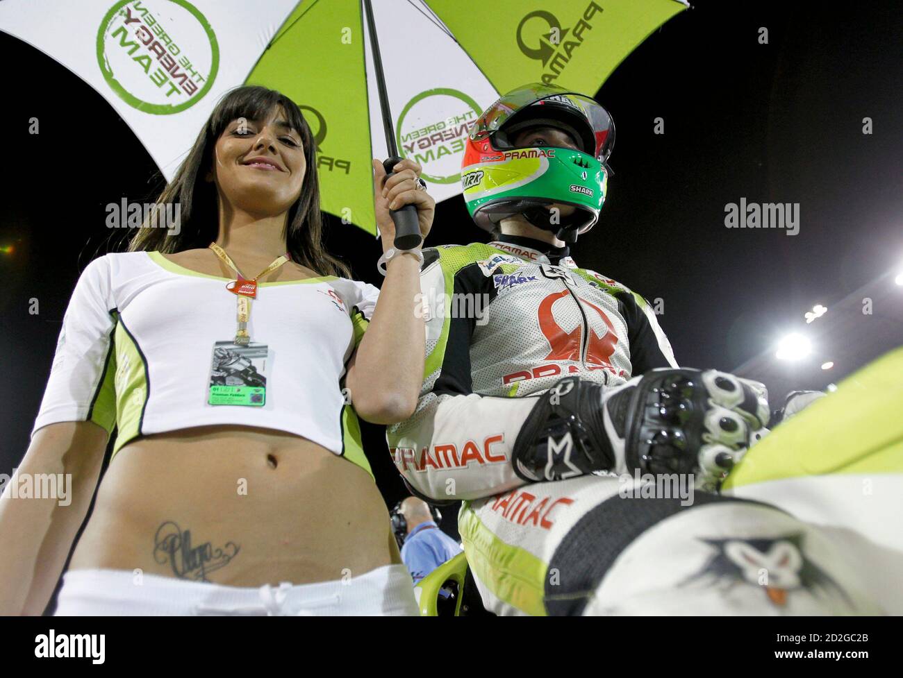 Eine Raster Mädchen schützt Pramac Racing MotoGP-Pilot Aleix Espargaro (R)  von Spanien vor dem Start ein Rennen in der MotoGP-Weltmeisterschaft auf  dem Losail international Circuit in Doha 11. April 2010. REUTERS/Fadi  Al-Assaad (