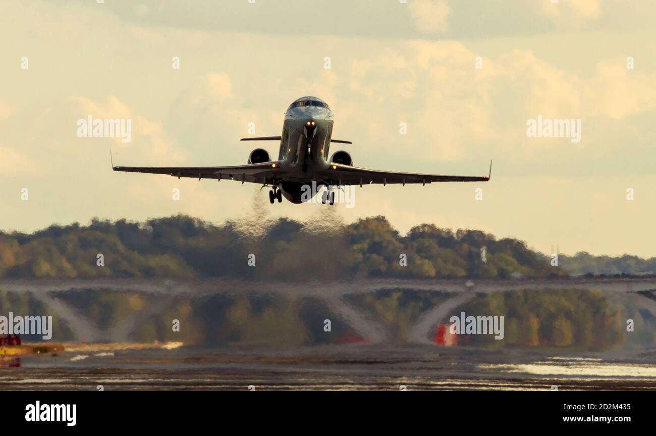 Ein Passagierflugzeug fliegt bei Sonnenuntergang von der Start- und Landebahn eines Flughafens ab. Die Absaugung und Verdunstung von Strahlkraftstoff erzeugt massive Unschärfen und Luft p Stockfoto