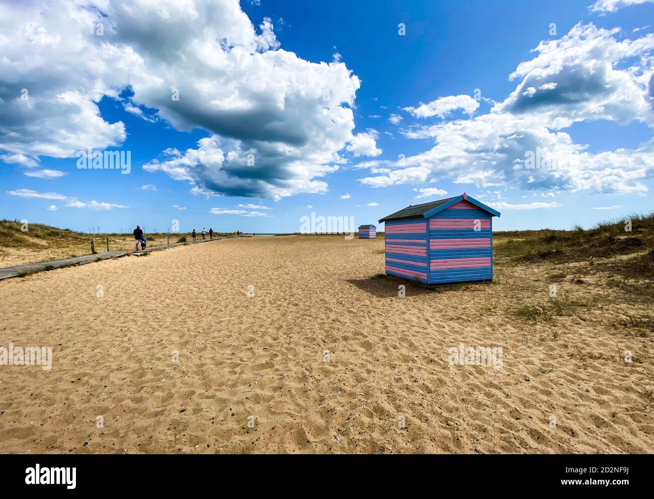 Tolle Strandhütten in Yarmouth an einem Sommertag, traditionelle britische Hütte an einer englischen Ostküste, blaue und rosa horizontale Streifen, Himmel mit Wolken ohne Peopl Stockfoto