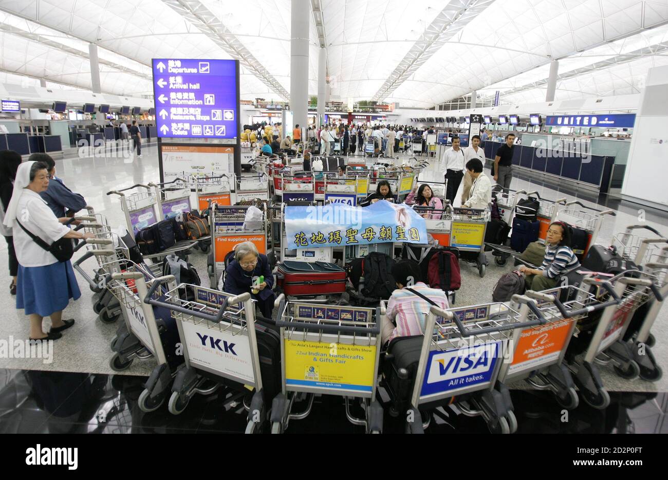 Passagiere warten auf den Abflug am internationalen Flughafen Hongkong am 3. August 2006. Obwohl Hongkong wahrscheinlich von Prapiroon nicht direkt getroffen werden kann, haben starke Winde 159 Flüge verzögert, während 92 gestrichen und 70 an andere Orte umgeleitet wurden, so die Flughafenbehörde. Rund 3,000 Passagiere wurden am Flughafen angesetzt, weitere 300 Flüge dürften bis Mitternacht unterbrochen sein. REUTERS/Paul Yeung (HONGKONG) Stockfoto