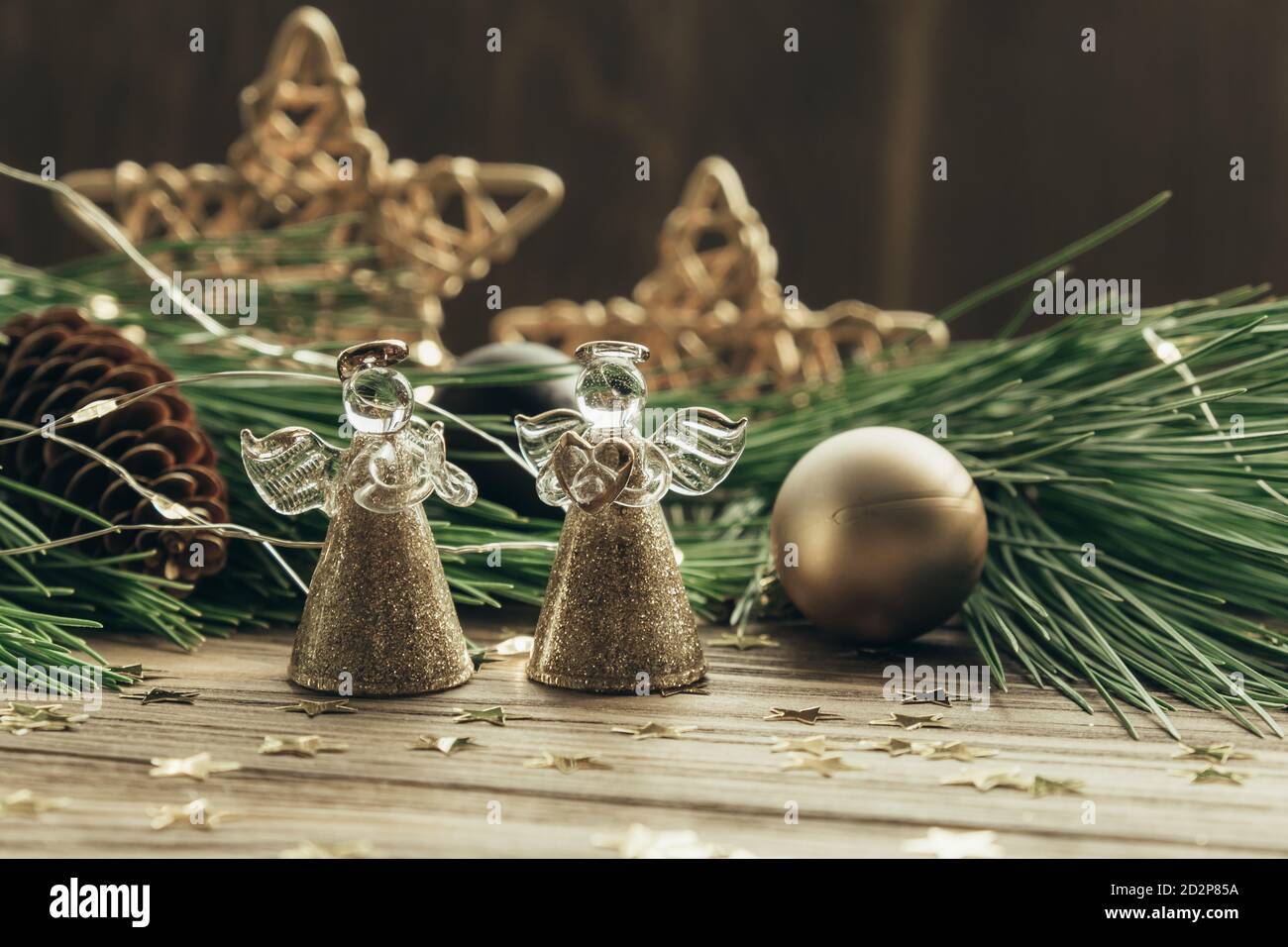 Weihnachtliche festliche Kulisse mit zwei Engeln, Tannenzweigen, Dekorationen und einer Girlande auf einem hölzernen Hintergrund. Frohe Weihnachten. Selektiver Fokus. Stockfoto