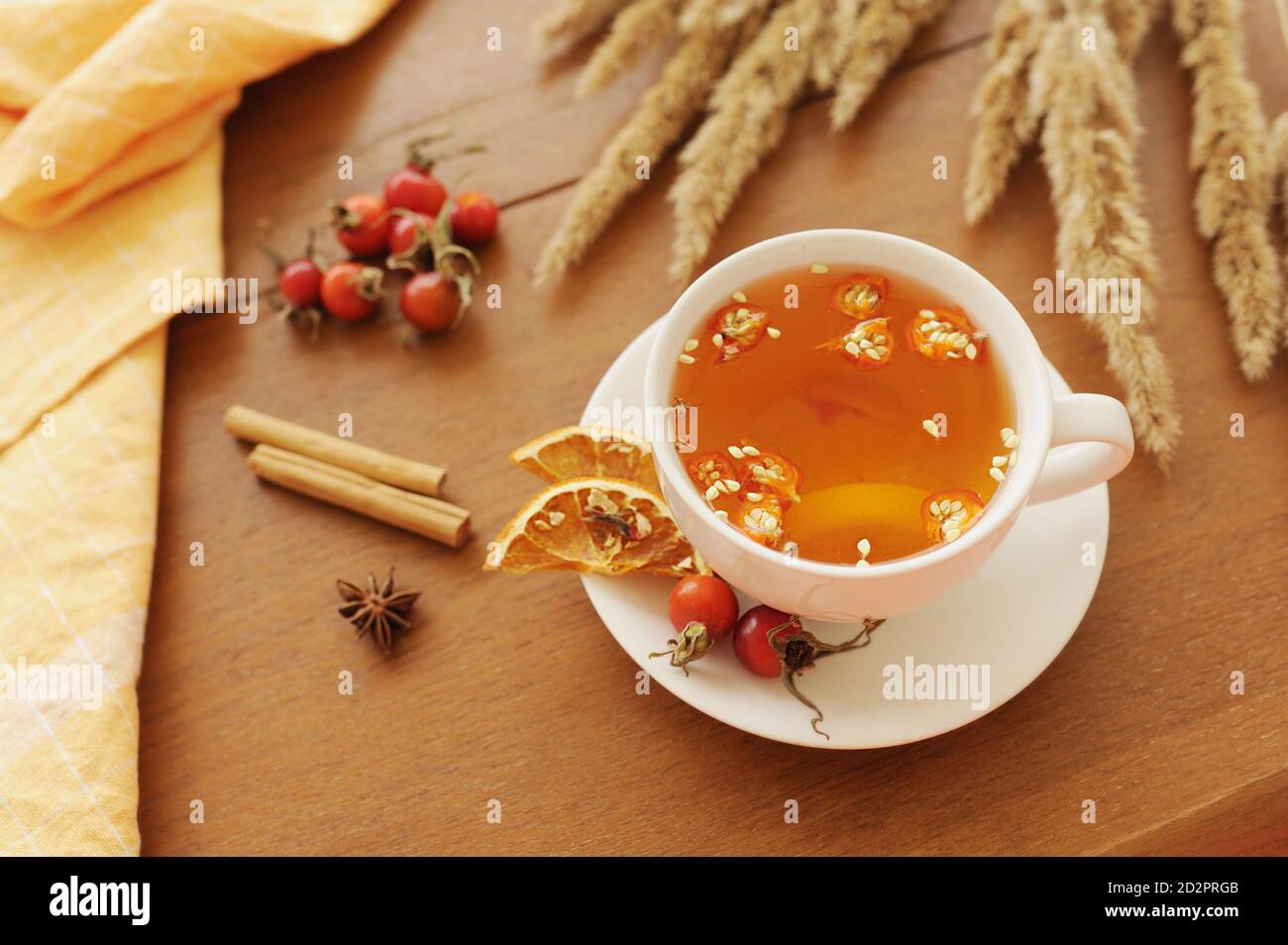 Gesunde Herbst Vitamin-Tee Hagebutten Beeren, Zitrone und Zimt auf Holztisch mit Bouquet von getrockneten Blumen und Baumwolle Serviette, gemütlich wärmende Tee Teil Stockfoto