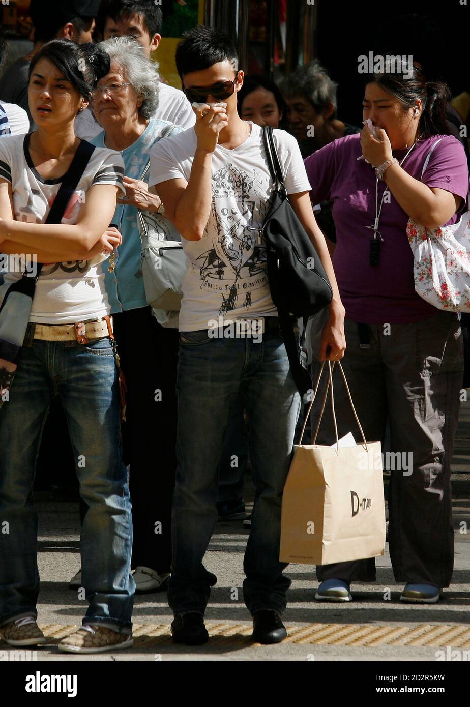 Fußgänger decken ihre Nase und Mund, während sie darauf warten, eine Straße in Hong Kong Einkaufsviertel Causeway Bay zu überqueren, 15. Juli 2009. Luftverschmutzung in Hongkong hat das Sechsfache sprang in den vergangenen vier Jahren, aber Experten sagen lokale Fahrzeuge mehr Schuld als Smog eingeblasen vom südlichen China Herstellung Gürtel sind, eine Zeitung berichtete am Mittwoch.   REUTERS/Bobby Yip (CHINA-Politik-BUSINESS-Umgebung) Stockfoto