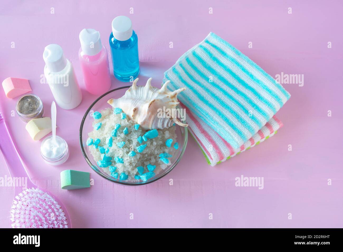 Spa-Körperpflege-Konzept. Meersalz zum Peeling, reinigungsmittel, Handtücher auf rosafarbenem Holzhintergrund. Stockfoto