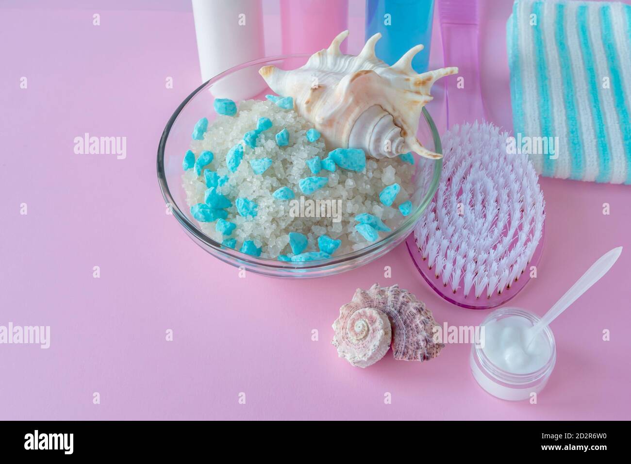Salz mit Toten Meer Mineralien und Massagebürste auf rosa Hintergrund. SPA-Konzept, Körper- und Hautreinigung, Entspannung. Stockfoto