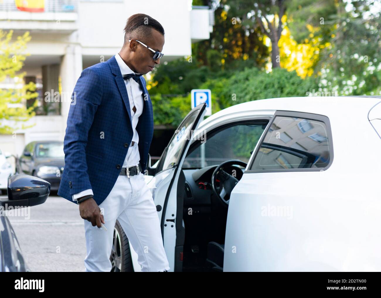 Seitenansicht des ernsten afroamerikanischen männlichen Unternehmers, der die Tür schließt Von Luxus-Automobil auf der Straße in der Stadt geparkt Stockfoto