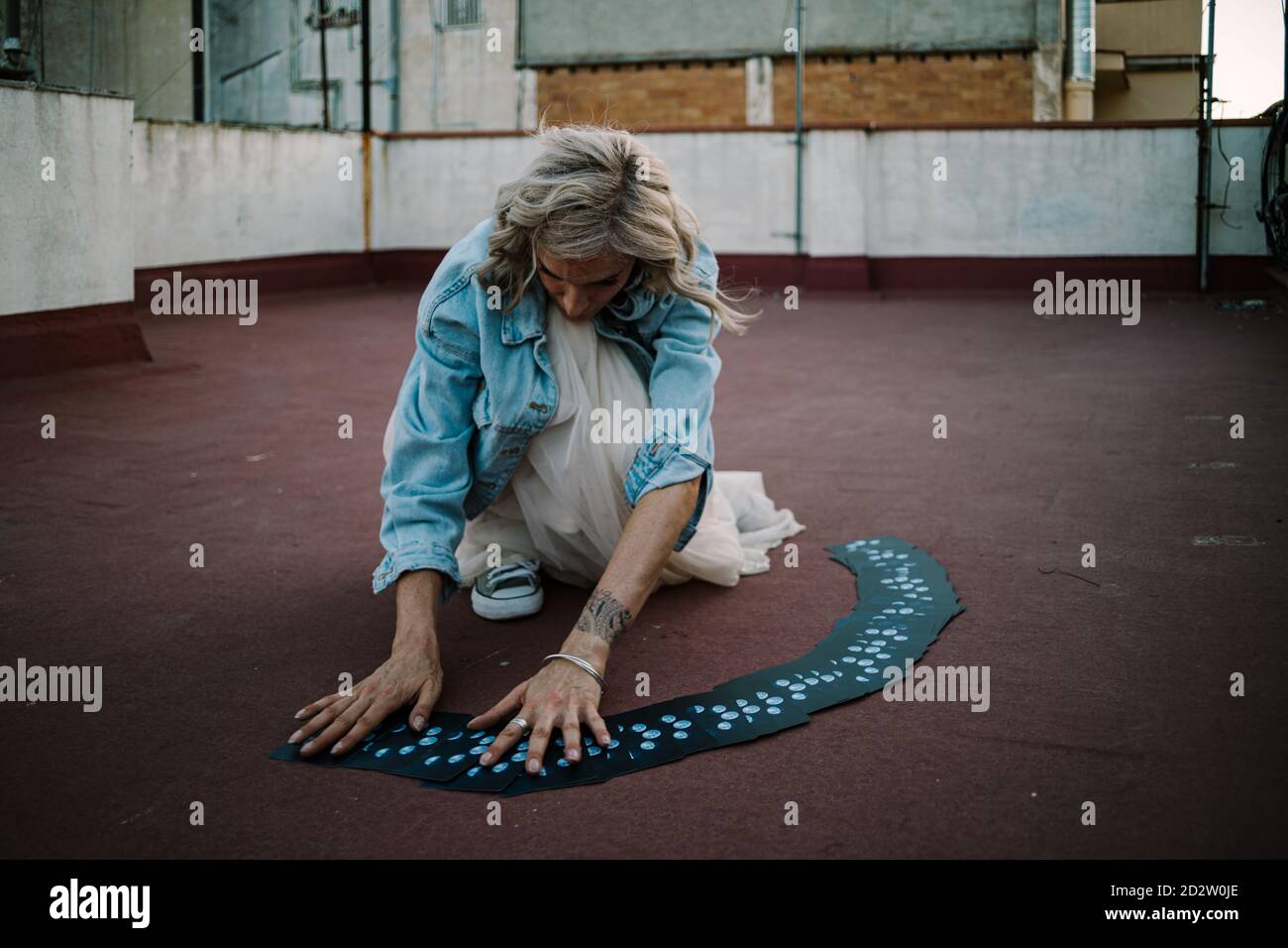 Ernsthafte weibliche Wahrsagerin beim Lesen von Tarot-Karten während des Sitzens Dach des alten Gebäudes Stockfoto