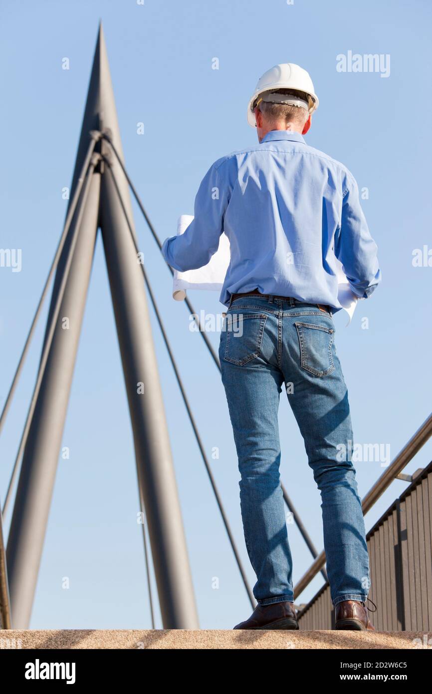 Reifer Architekt oder Ingenieur, der mit Blaupause davor steht Konstruktion - Fokus auf den Mann Stockfoto