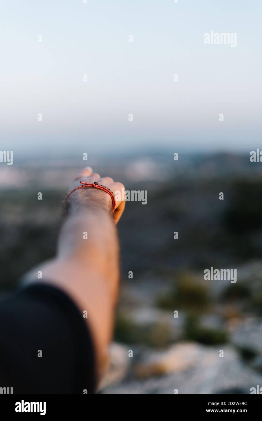 Crop unkenntlich männlichen Reisenden stehen auf felsigen Hügel und zeigt Weg vor verschwommener Berglandschaft Stockfoto