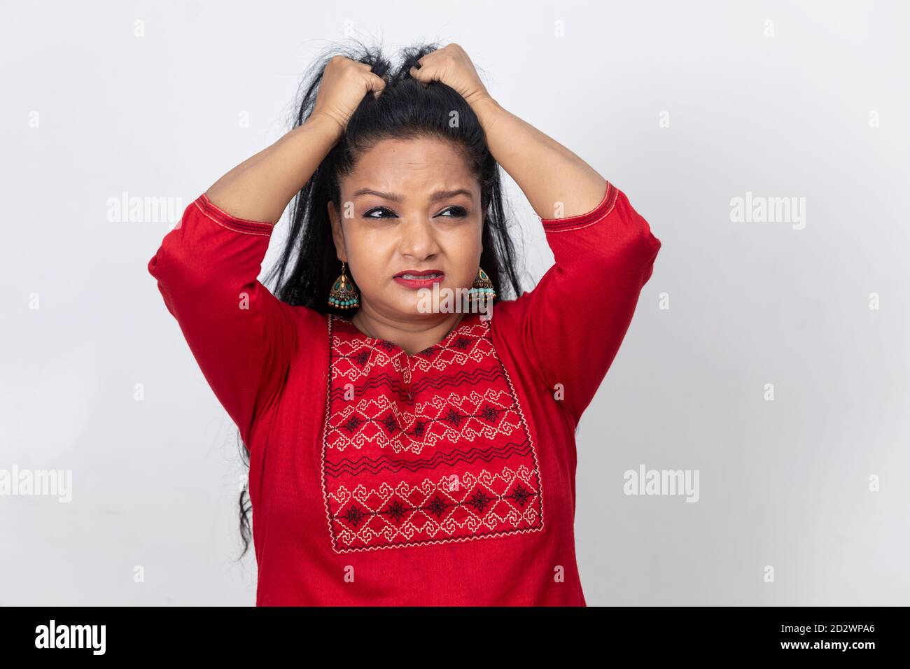 Porträt einer indischen Frau mit ihren Fingern in ihren langen Haaren und an ihnen ziehen, wütend und frustriert Dame. Stockfoto