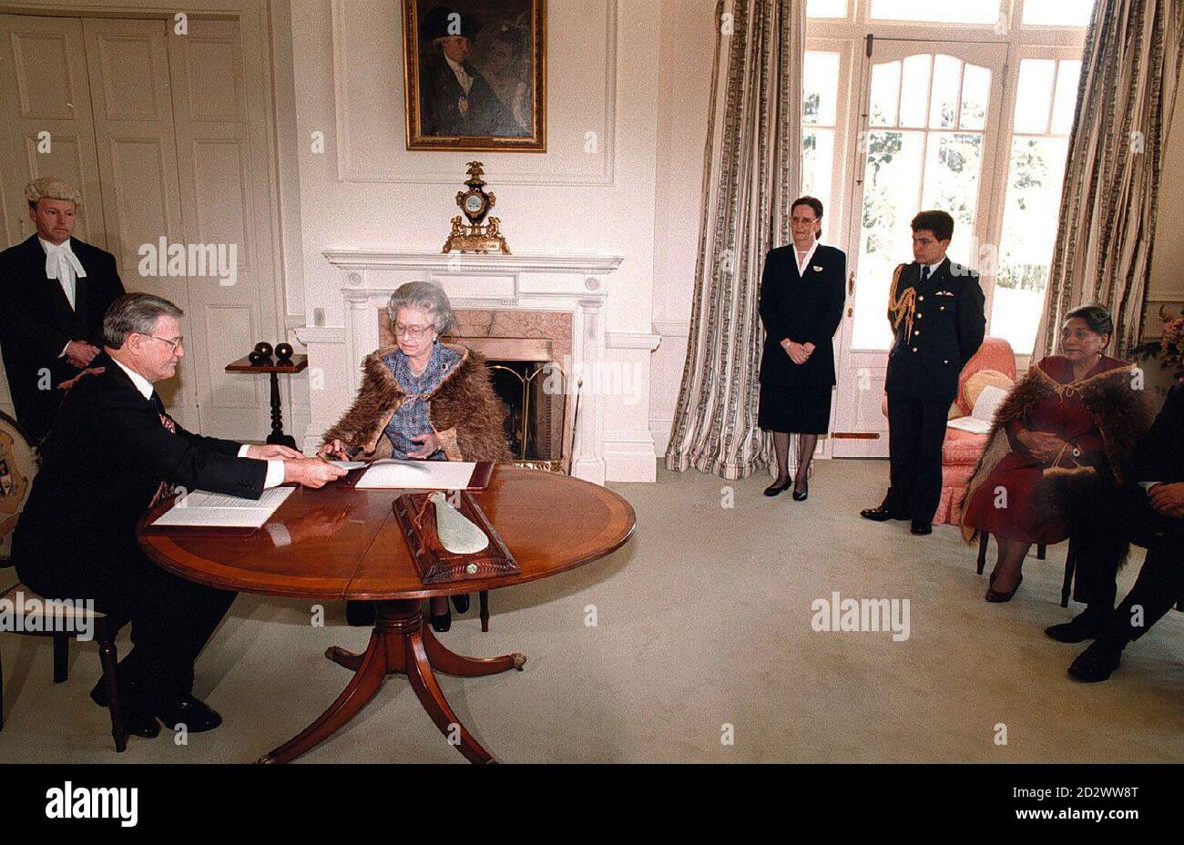 Die Königin unterschreibt das Waikato Raupatu Claims Settlement Bill im Government House in Wellington. An der kurzen Zeremonie nahmen der neuseeländische Premierminister James Bolger (links) und die Maori-Königin Dame Te Atairangikaahu (rechts) Teil. Stockfoto