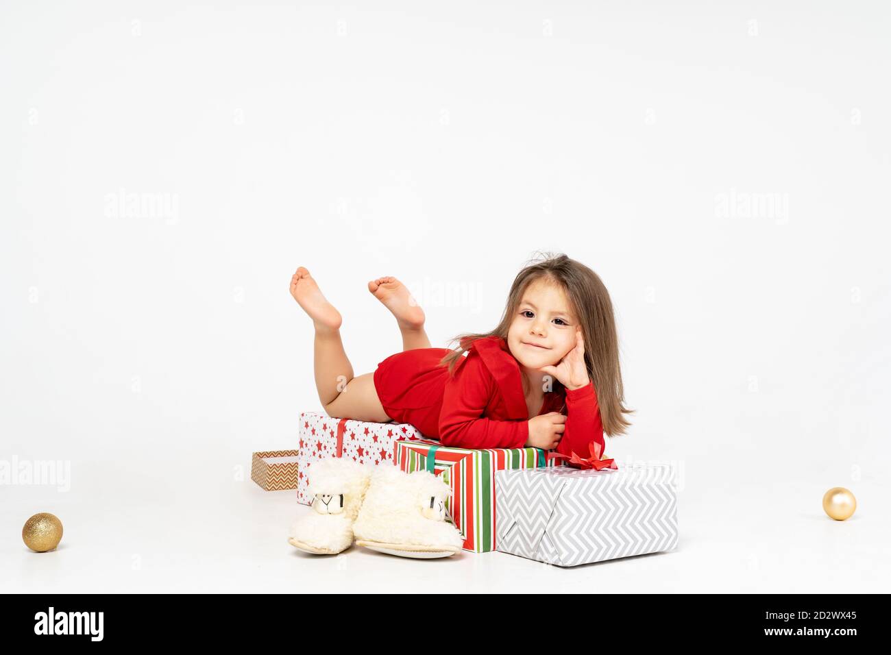 Neujahr Bild: Ein kleines Mädchen liegt auf den Geschenken, die der Weihnachtsmann ihr mitgebracht hat Stockfoto