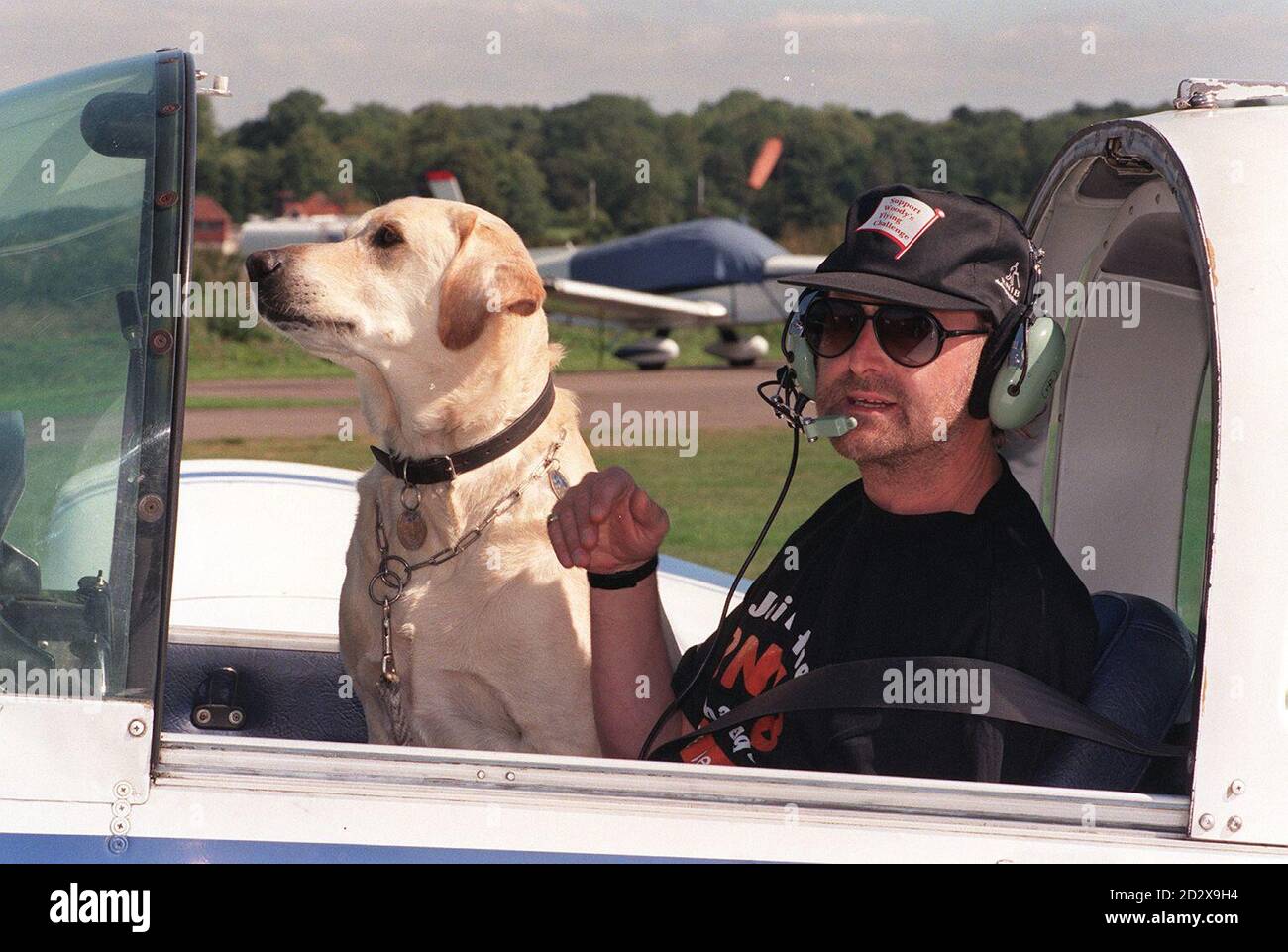 Der blinde Pilot Ken Woodward, mit seinem Führhund Prince, im Cockpit seines Flugzeugs, bevor er heute (Freitag) von Elstree auf einen Rundflug durch Großbritannien zur Wohltätigkeitsorganisation abhebt. Herr Woodward aus Brightlingsea, Essex, der nach einer chemischen Explosion sein Augenlicht verloren hat, wird neun Tage auf dem Flug verbringen und auf der Strecke Prominente treffen. Siehe PA Story AIR Blind. PA Foto von Mike Stephens/PA Stockfoto