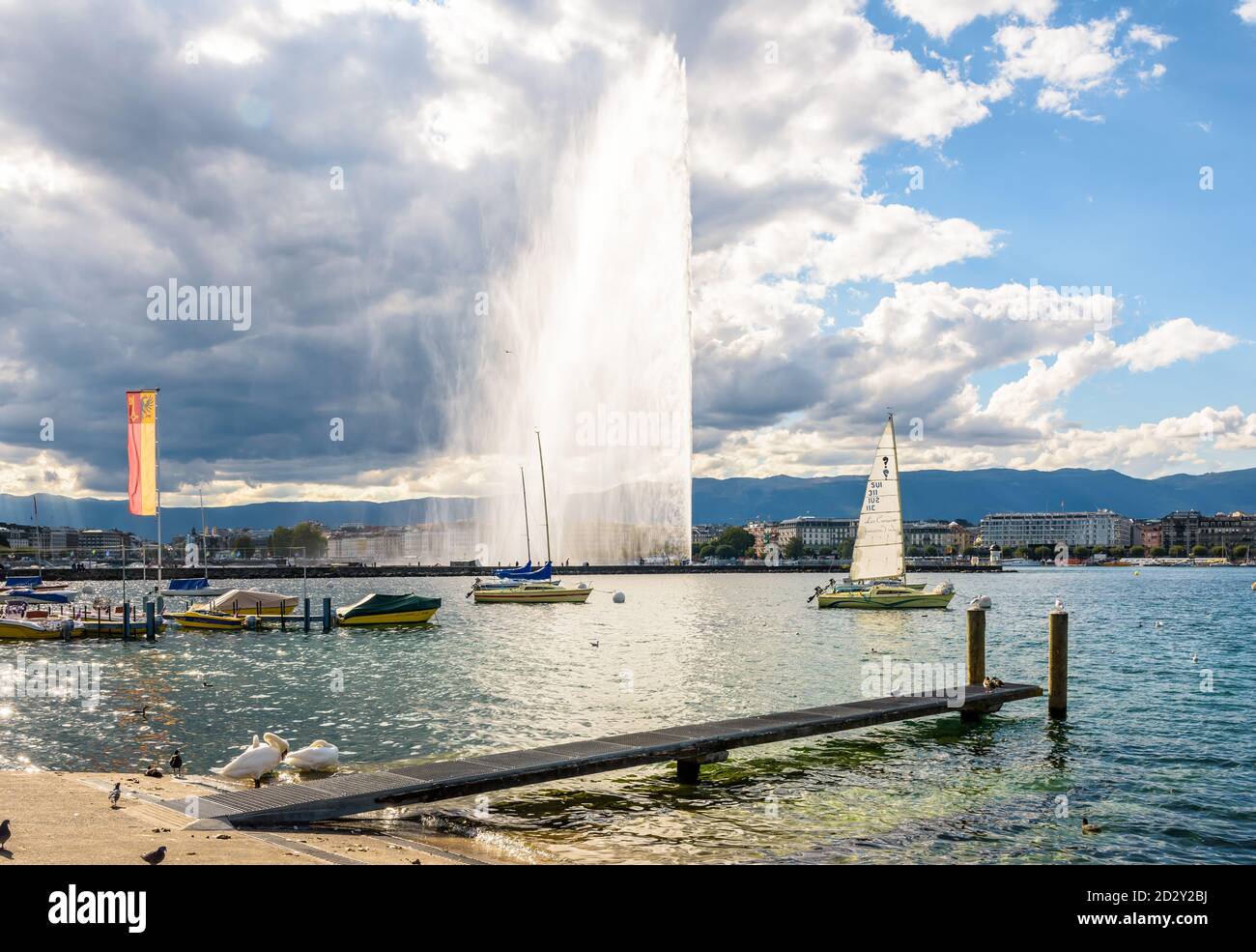 Der Jet d'Eau in der Genfer Bucht, Schweiz, der 140 Meter hohe Wasserstrahl auf dem Genfersee, Wahrzeichen der Stadt, an einem stürmischen späten Nachmittag. Stockfoto