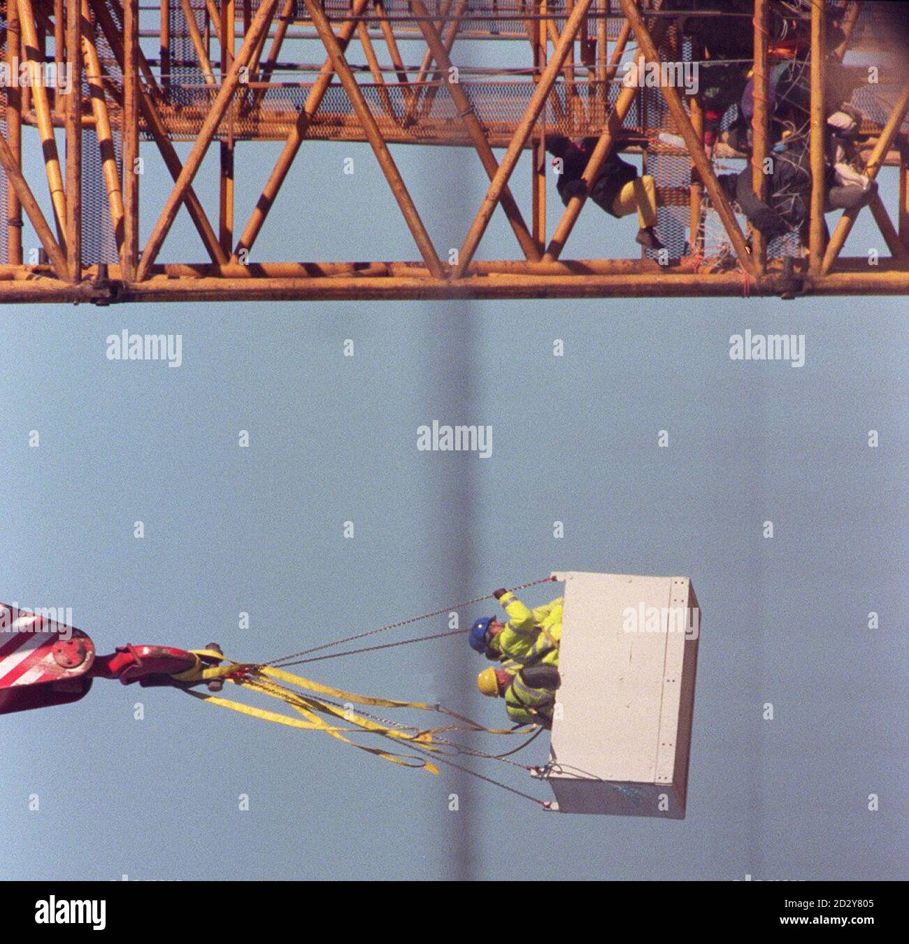 Beamte (links) versuchen, die Demonstranten (rechts) vom Absinken zu überzeugen, nachdem sie einen riesigen Kran bestiegen haben, der heute (Dienstag) für die Installation der 12 Masten verwendet wird, die zur Unterstützung der Struktur des Millennium Dome in Greenwich benötigt werden. Neun Aktivisten, die sich selbst Time Bomb nannten, ketteten sich an den 350 Meter langen Kran und entrollten ein Transparent mit der Aufschrift: Domesday Dome. Foto von David Giles. Siehe PA Story MILLENNIUM Protest. Stockfoto