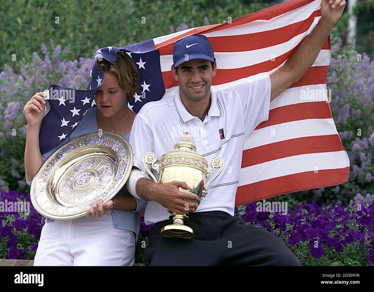 Keine kommerzielle Nutzung : die Wimbledon-Einzelgewinner Lindsay Davenport und Pete Sampras kämpfen mit der amerikanischen Flagge, nachdem der Wind sie bei einem Fotoanruf in Wimbledon verschlang. Sampras besiegte Agassi 6-3 6-4 7-5 und Davenport besiegte Graf 6-4 7-5. Stockfoto