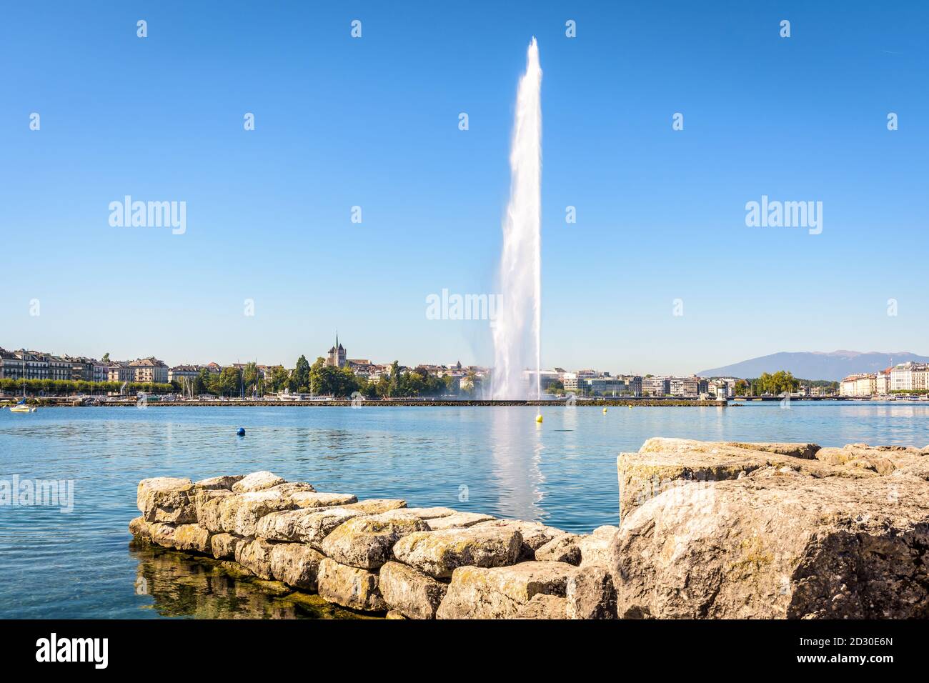 Die Stadt und die Bucht von Genf, Schweiz, mit ihrem Wasserstrahlbrunnen auf dem Genfer See, von einem Steinsteg aus gesehen von einem sonnigen Sommermorgen. Stockfoto